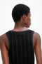 A person with short curly hair is shown from the back wearing Victoria Beckham's Fine Knit Vertical Stripe Tank In Black-Blue, reminiscent of her sleek designs.