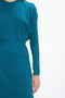 Person wearing a long-sleeved teal Long Sleeve Dolman Midi Dress In Petroleum by Victoria Beckham, with a focus on the upper torso and right arm, exuding contemporary sophistication through its fluid cady fabric.