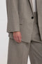 Close-up of a person wearing a dogtooth check Victoria Beckham Peak Lapel Jacket In Multi, featuring a peak lapel jacket with their left hand visible near their side. The suit has a single-button closure and is paired with matching trousers.