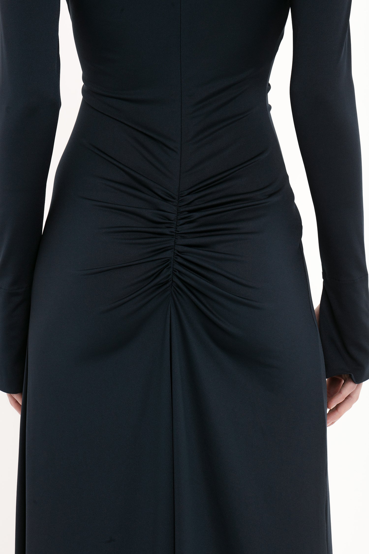 Close-up of the back of a person wearing a Ruched Detail Floor-Length Gown In Midnight by Victoria Beckham with ruched detail along the center seam.