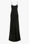 A black, floor-length, sleeveless **Floor-Length Cami Dress In Black** with thin spaghetti straps and a smooth, flowing texture reminiscent of 90s fashion from **Victoria Beckham**.