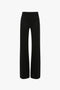 A pair of black trousers viewed from the back, featuring belt loops, two back pockets, and straight legs. Designed with subtle nods to 70s style references, these Victoria Beckham Alina Tailored Trouser In Black add a touch of retro sophistication.