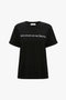 A black organic cotton T-shirt with rolled-up sleeves, featuring white text that reads, "Paris streets are my Runway," the PARIS STREETS ARE MY RUNWAY T-shirt in Black by Victoria Beckham.