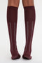 Rear view of a person wearing Victoria Beckham Superfine Rib Socks In Burgundy, featuring a burgundy and white design with vertical white stripes down the back.