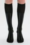 A pair of legs wearing contemporary design black knee-high socks, each with two vertical blue stripes down the front. These Superfine Rib Socks In Black by Victoria Beckham are a wardrobe essential.