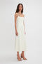 A woman with long dark hair is wearing a sleeveless, cream-colored Exclusive Panelled Midi Cami Dress In Vanilla by Victoria Beckham with a square neckline and tan platform sandals. She stands against a plain white background, evoking the elegance of Victoria Beckham's fashion style.