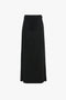 A sophisticated, floor-length black skirt with clean lines features a high waist and a slight A-line shape, crafted from recycled wool. Introducing the Tailored Floor-Length Skirt In Black by Victoria Beckham.