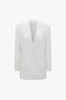 A white, double-breasted blazer with satin peak lapels, front flap pockets, and a structured silhouette. The Exclusive Double Breasted Tuxedo Jacket In Ivory by Victoria Beckham brings a tuxedo style elegance to your ensemble.