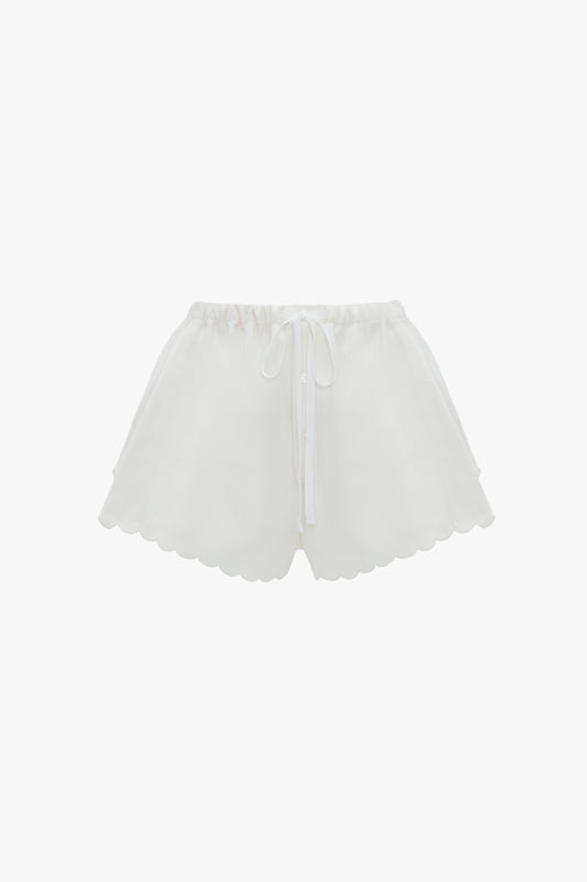 Drawstring Embroidered Mini Short In Antique White by Victoria Beckham, crafted from an antique white linen-cotton blend, feature an elastic waistband and drawstring tie, accented with delicate embroidered detailing. Displayed against a white background.