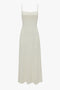 An Exclusive Panelled Midi Cami Dress In Vanilla designed by Victoria Beckham with narrow shoulder straps and a sleek square neckline, displayed against a white background.