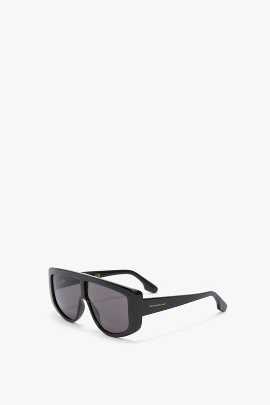 Acetate Visor Sunglasses In Black with oversized frames, dark tonal lenses, and gold detailing on the frame's temple—exuding the timeless elegance of Victoria Beckham eyewear.