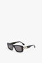 A pair of black rectangular Chain Detail Rectangular Frame Sunglasses In Black by Victoria Beckham with dark lenses and a silver metallic accent on the arms, set against a white background.