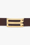 A close-up of the Victoria Beckham Exclusive Frame Belt In Burgundy Leather featuring a unique gold buckle with a geometric design.