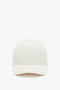 Front view of a plain beige Logo Cap In Antique White by Victoria Beckham against a white background.