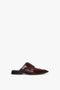 A single Flat Lace Up Mules In Bordeaux Leather by Victoria Beckham with a closed toe design, decorative stitching, and a black rubber sole, shown against a white background.