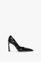 Side view of a single black high-heeled shoe with a pointed toe, glossy finish, and sculptural heel showcasing a signature V motif. Presenting the Victoria Beckham V Pump In Black Brushed Leather.