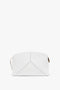 An **Exclusive Victoria Clutch Bag In White Leather** with geometric stitching, gold zipper, and minimal branding showcases a structured design in true **Victoria Beckham** fashion.