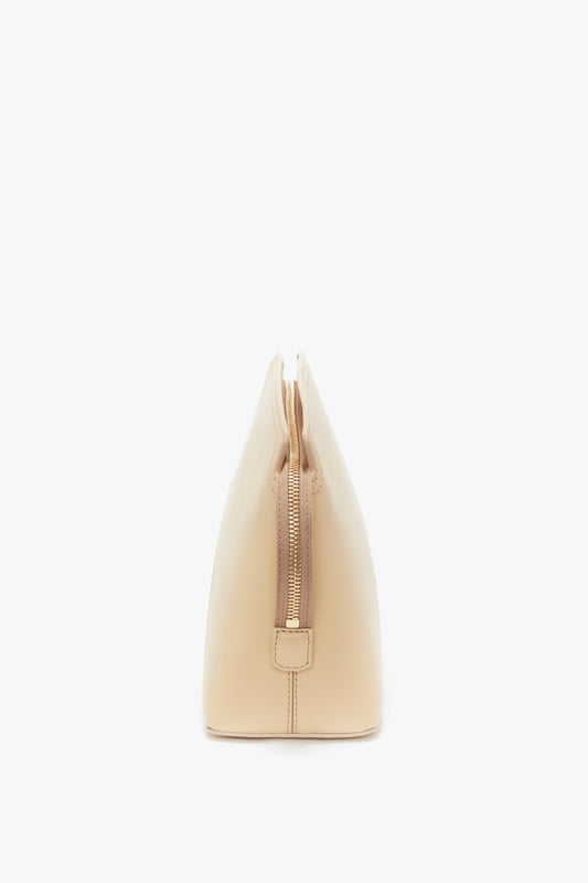 Side view of a beige calf leather Victoria Clutch Bag In Sesame Leather by Victoria Beckham with a visible zipper running across the top, echoing the refined elegance seen on the SS24 runway.