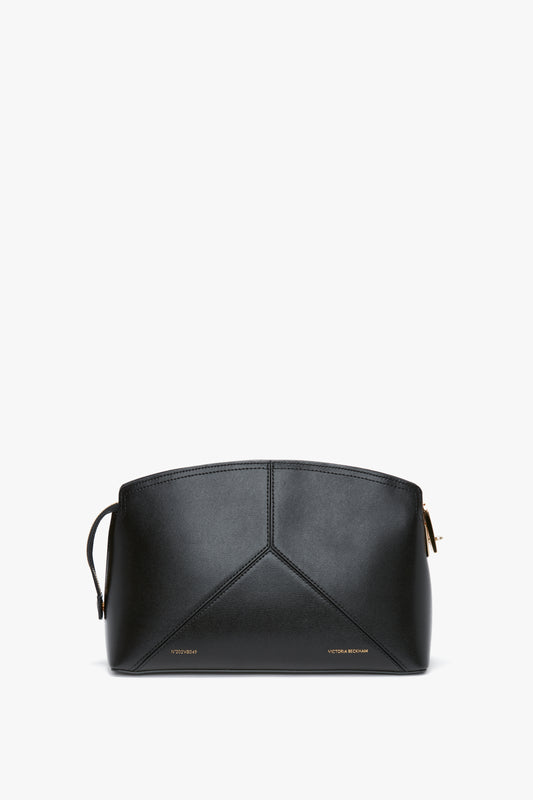 A Victoria Beckham Victoria Clutch Bag In Black Leather with a unique geometric design on the front, small gold text at the bottom, and a structured silhouette reminiscent of Victoria Beckham leather goods.