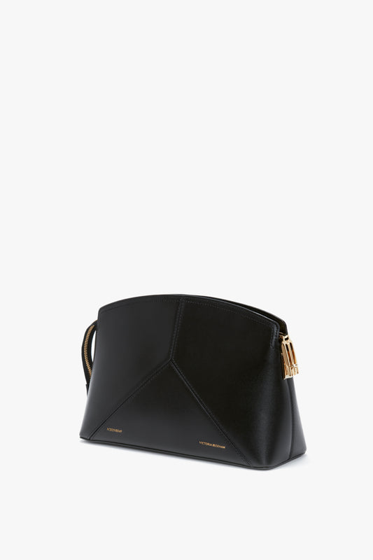 A **Victoria Clutch Bag In Black Leather** by **Victoria Beckham**, featuring a structured silhouette with gold accents and a geometric design on a white background.