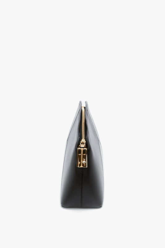 Side view of a black leather Victoria Beckham Victoria Clutch Bag In Black Leather with gold-tone zipper and minimalistic design against a white background, showcasing a structured silhouette.