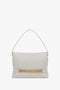 A Puffy Chain Pouch With Strap In White Leather by Victoria Beckham featuring a single shoulder strap and a striking gold chain detail across the front.