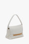 A white leather Victoria Beckham Puffy Chain Pouch With Strap In White Leather with a single strap and a folded top, featuring a gold chain detail across the bottom of the flap.