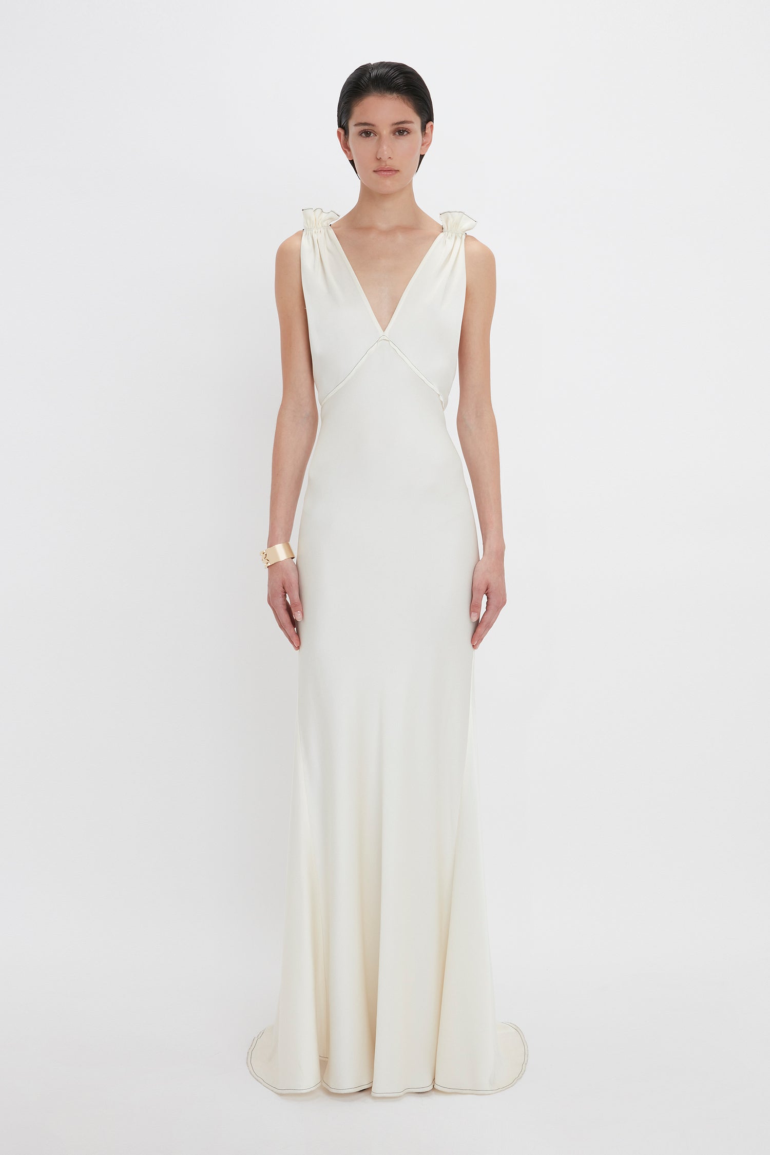 A person wearing a Gathered Shoulder Floor-Length Cami Gown In Ivory by Victoria Beckham stands against a plain white background.