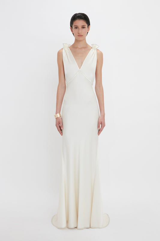 A person wearing a Gathered Shoulder Floor-Length Cami Gown In Ivory by Victoria Beckham stands against a plain white background.