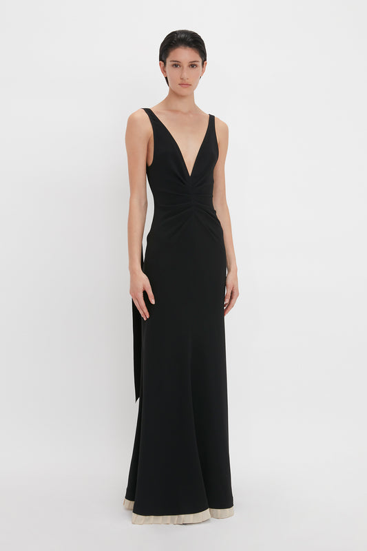 Person wearing a Victoria Beckham V-Neck Gathered Waist Floor-Length Gown in Black, standing against a plain white background.