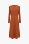 An elegant long-sleeve Dolman Midi Dress In Russet by Victoria Beckham with a fitted waist and a flared skirt, isolated on a white background.