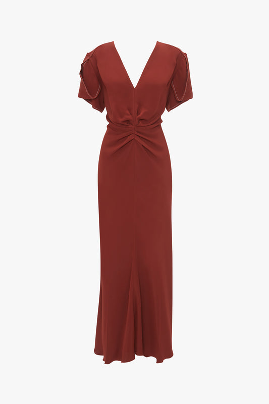 The Victoria Beckham Gathered V-Neck Midi Dress In Russet features short ruffled sleeves and a figure-flattering stretch fabric. The dress boasts a gathered knot design at the waist and extends to a midi length with a subtle front slit.