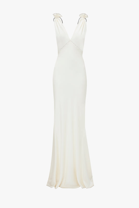A stunning backless, floor-length sleeveless white gown with a deep V-neck and minimalistic design, crafted from luxurious crepe back satin. Introducing the Gathered Shoulder Floor-Length Cami Gown In Ivory by Victoria Beckham.