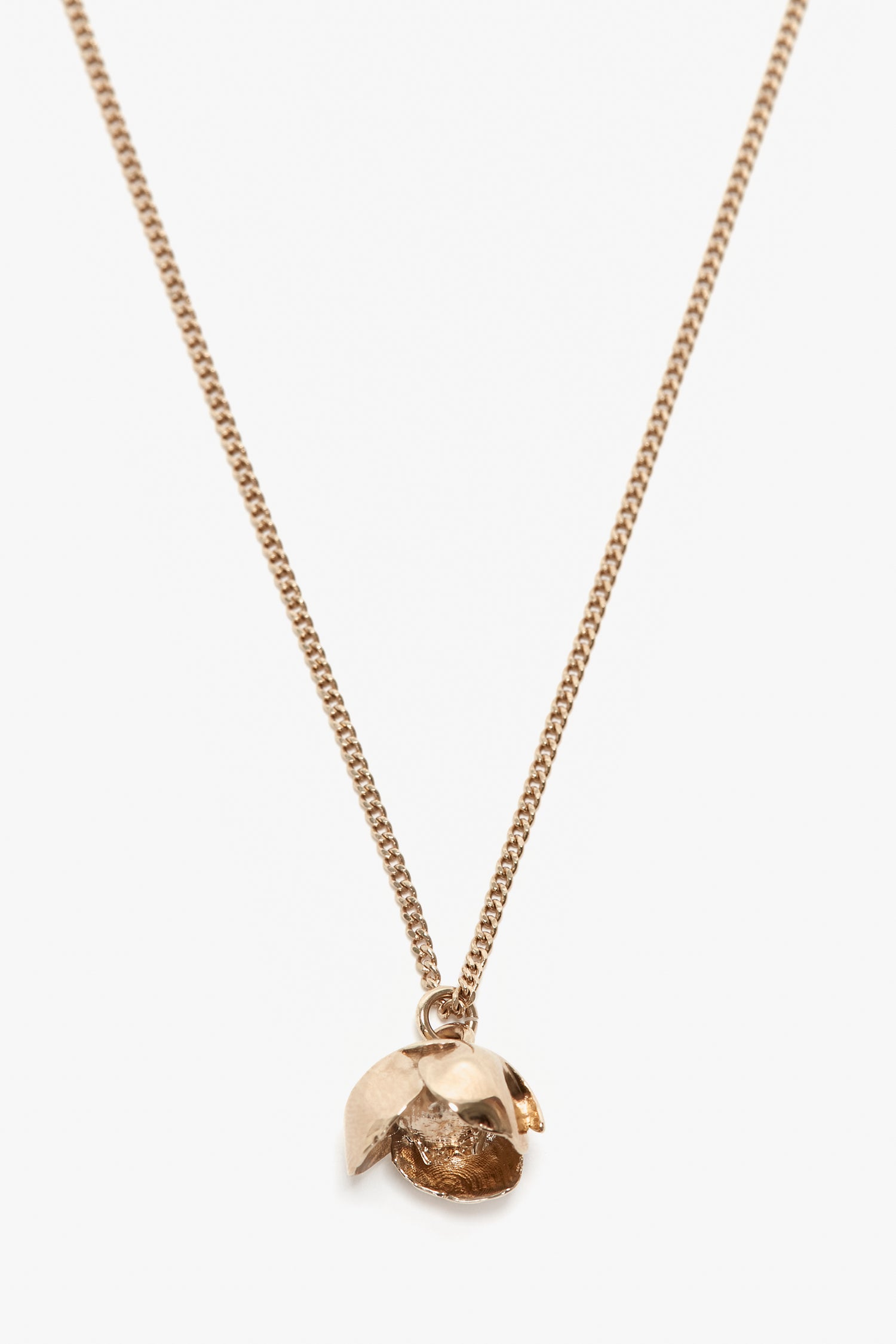 A gold chain necklace with a unique, shell-like pendant reveals a textured, metallic interior, reminiscent of the delicate beauty found in an Exclusive Camellia Flower Necklace In Gold by Victoria Beckham, handcrafted in Italy.