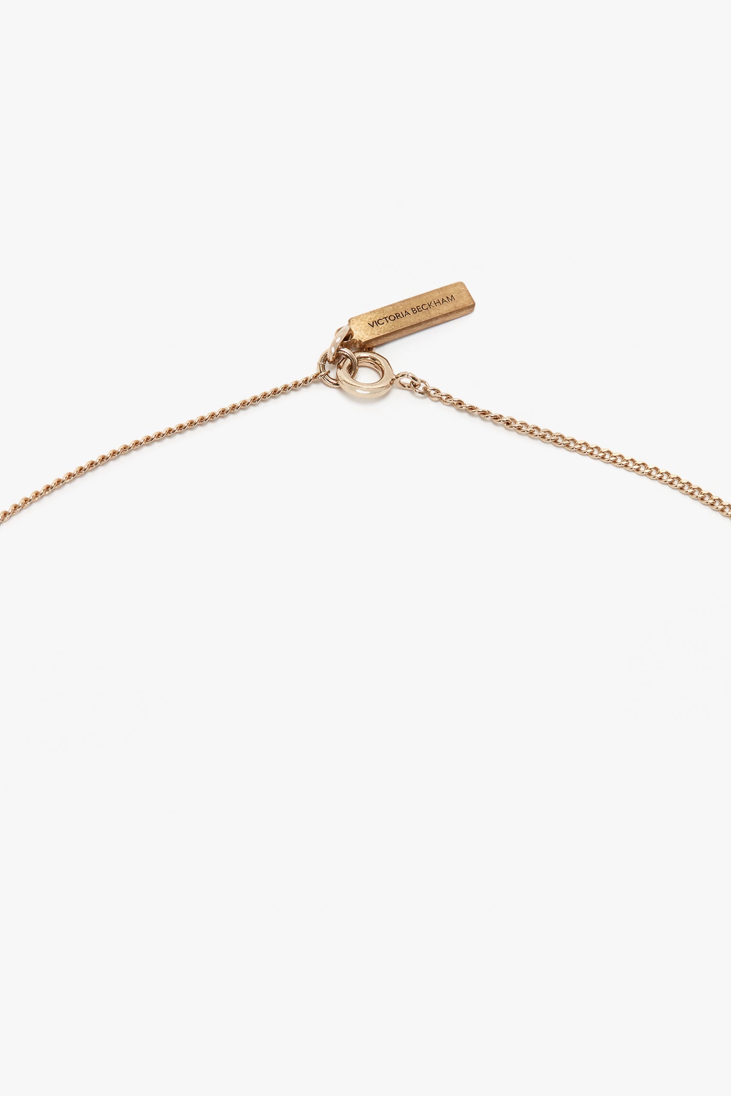 A delicate Exclusive Camellia Flower Necklace In Gold with a small rectangular tag reading "Victoria Beckham," handcrafted in Italy.
