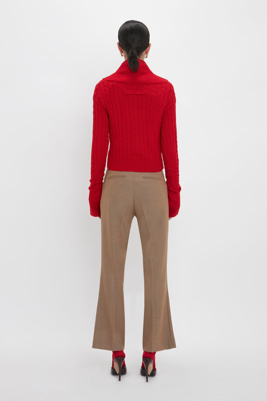 Person in a red turtleneck sweater and Victoria Beckham's Wide Cropped Flare Trouser In Tobacco, standing with their back to the camera, on a white background.