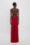 A person wearing a floor-length, Low Back Cami Floor-Length Dress In Poppy Red by Victoria Beckham, 1990s-inspired camisole-slip dress with thin straps and an open back stands facing away.