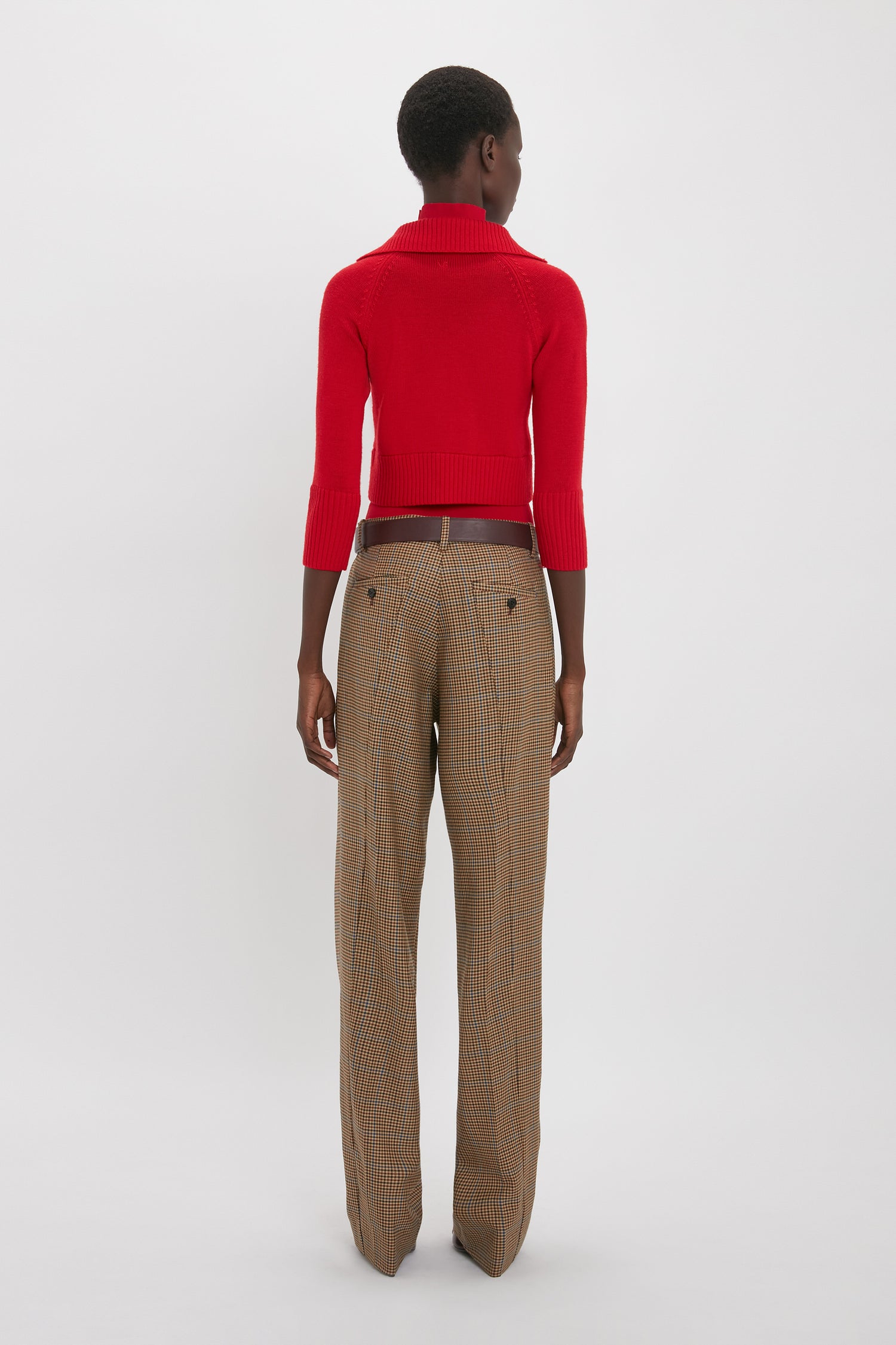 Person standing with their back facing the camera, wearing a Victoria Beckham Double Layer Top In Deep Red and brown plaid trousers.