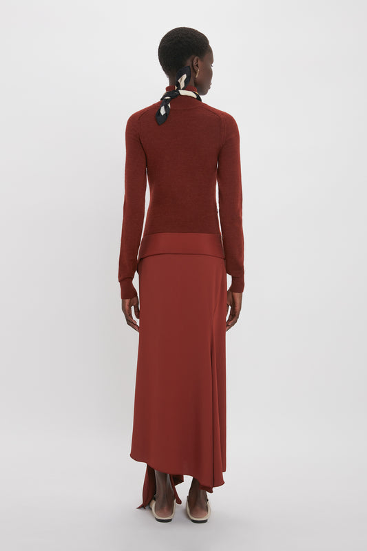 A person with short hair is seen from the back wearing a High Neck Tie Detail Dress In Russet, paired with beige shoes. The elegant red ensemble, reminiscent of Victoria Beckham's style, includes a matching red skirt.