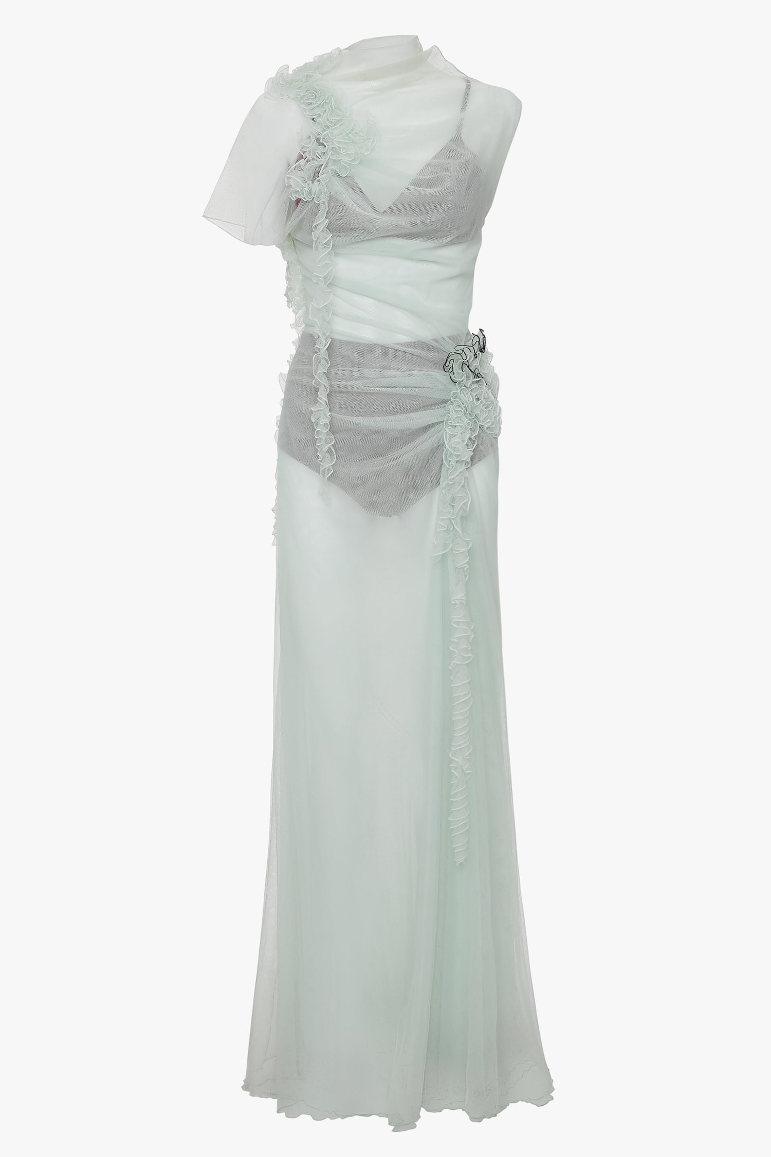 A sheer, flowing Victoria Beckham Gathered Tulle Detail Floor-Length Dress In Jade with an asymmetrical design, featuring a ruffled overlay and floral embellishment at the waist, in light pastel sea foam green tulle.