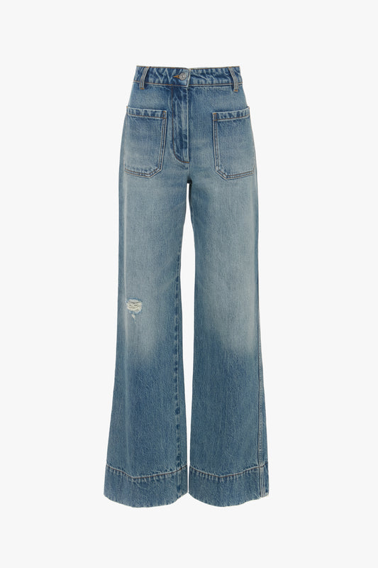 A pair of distressed Alina High Waisted Jean In Worn Blue Wash by Victoria Beckham with front patch pockets, belt loops, and a small rip on the left thigh.