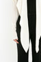 Cropped image of a person wearing the Victoria Beckham Oversized Bow Detail Blouse In Vanilla with black pants. Only their torso and part of their arm are visible, highlighting the dramatic finishing touch.