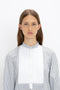 A person with long brown hair is wearing the Tuxedo Bib Shirt in Black and Off-White from Victoria Beckham, showcasing modern menswear silhouettes, standing against a plain white background.