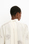 A person is seen from the back wearing the Victoria Beckham Asymmetric Gather Detail Top in Cream with a textured pattern, wide collar, and blouson sleeves.