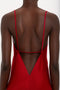 A person is shown from the back wearing a Low Back Cami Floor-Length Dress In Poppy Red by Victoria Beckham, with thin straps and a deep V-cut.