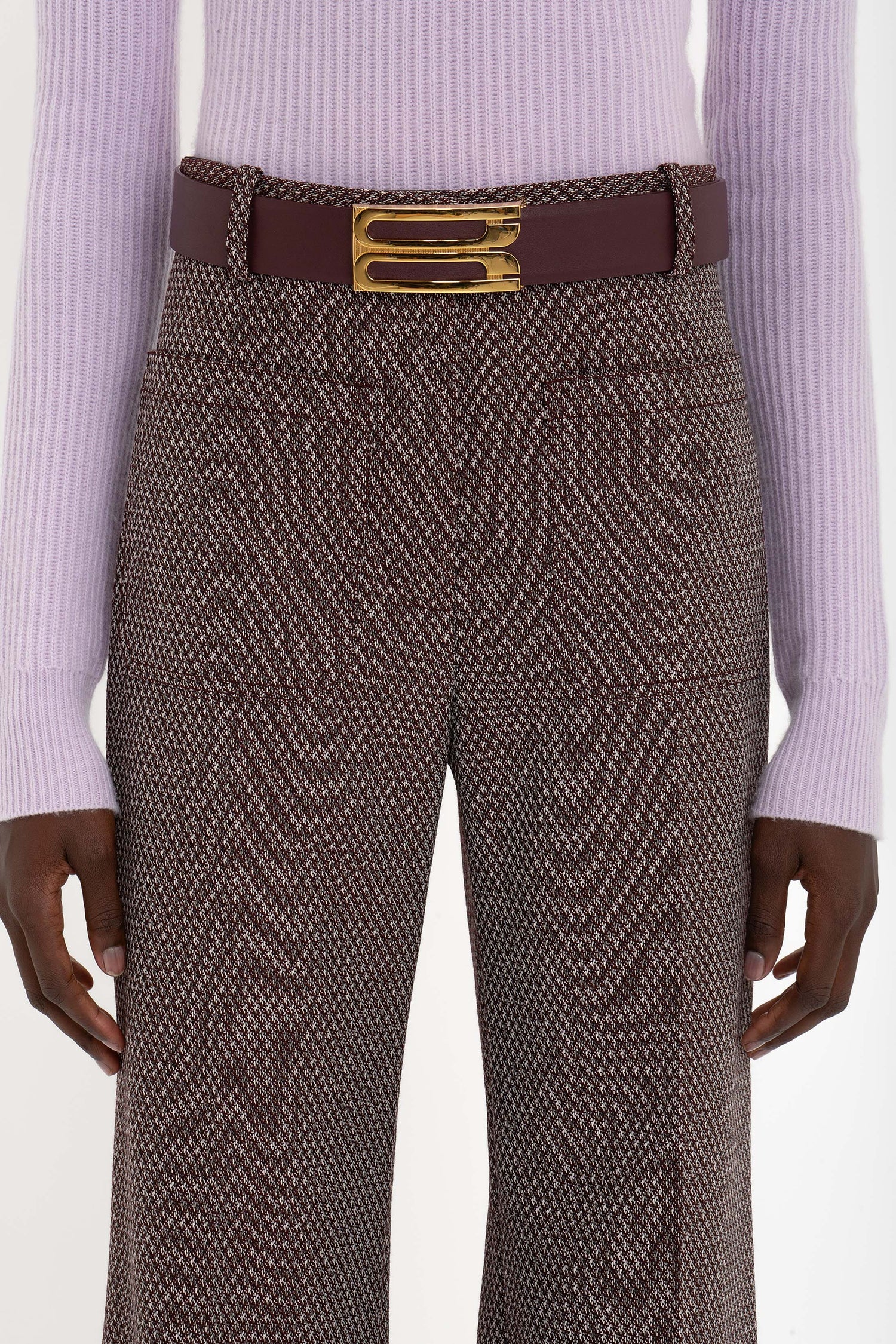 Person wearing a light purple sweater, Victoria Beckham Alina Trouser In Tobacco with a maroon belt featuring a gold buckle. The image is cropped to show only the torso and upper legs.