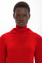 A person wearing a bright red, long-sleeved Victoria Beckham Double Layer Top In Deep Red with a serious expression looks directly at the camera against a plain white background.