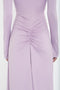 A close-up of the back of a person wearing a light purple Victoria Beckham Ruched Detail Floor-Length Gown In Petunia with long sleeves, crafted from stretch jersey and featuring a ruched detail at the center of the lower back.