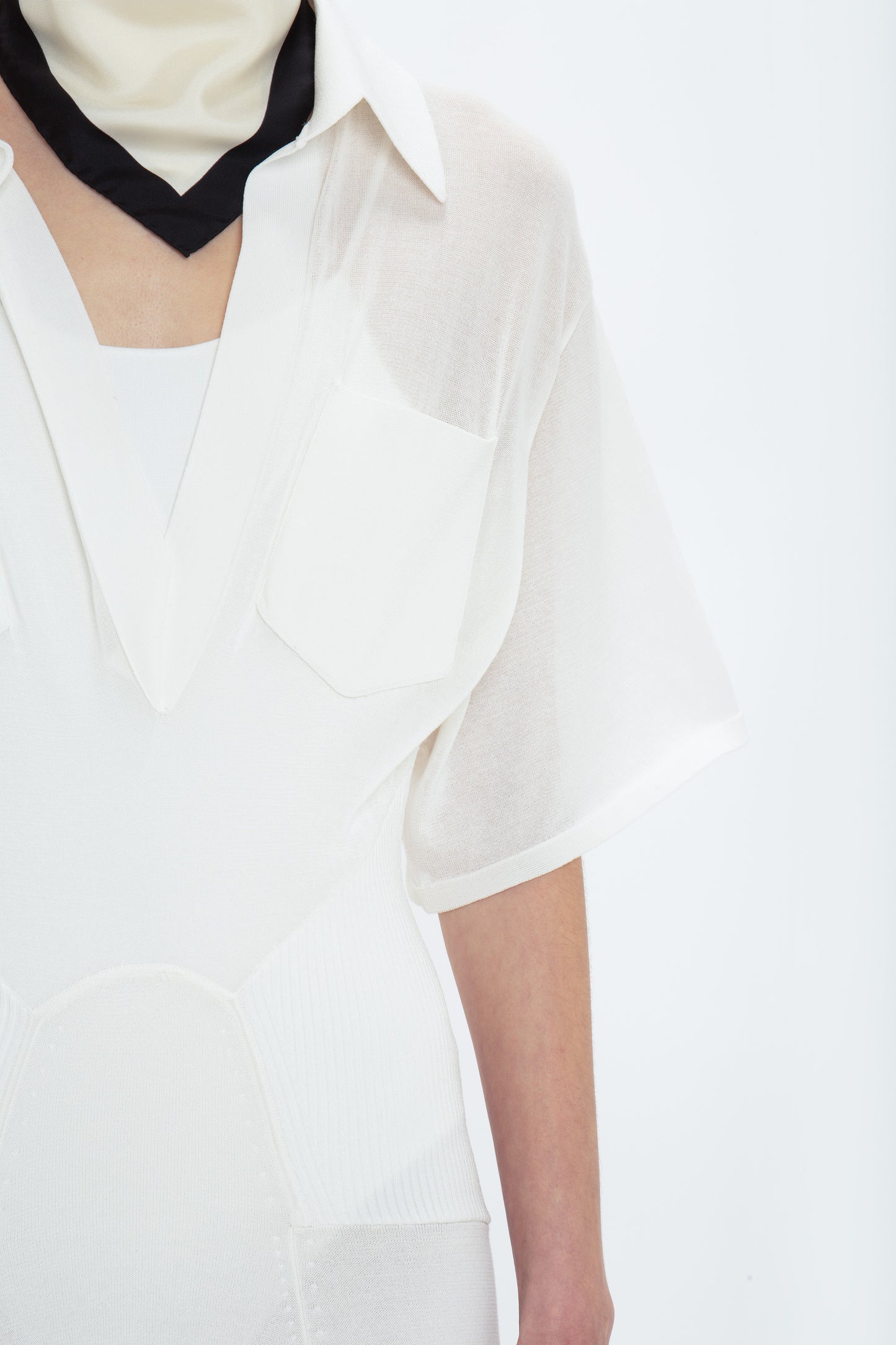 Close-up of a person wearing a Panelled Knit Dress In White by Victoria Beckham, exuding relaxed glamour. The image focuses on the torso, with no face visible.