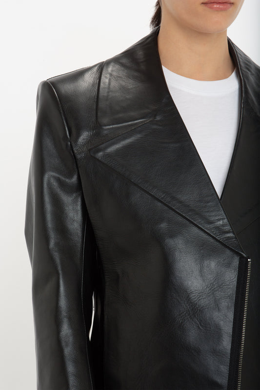 A person is wearing a Tailored Leather Biker Jacket In Black by Victoria Beckham over a white shirt, photographed from the shoulders down, presenting a structured silhouette that embodies modern classic style.